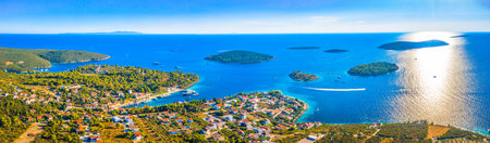 A breathtaking aerial panorama of Maslinica on Solta Island, Croatia, capturing its charming harbor, stone architecture, lush greenery, and the sparkling Adriatic Seaの写真素材