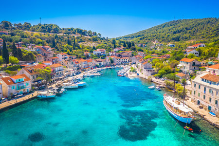 Aerial view of the tranquil bay in Stomorska on Solta Island, Croatia, featuring crystal-clear turquoise Adriatic waters, traditional seaside houses, and lush greeneryの写真素材