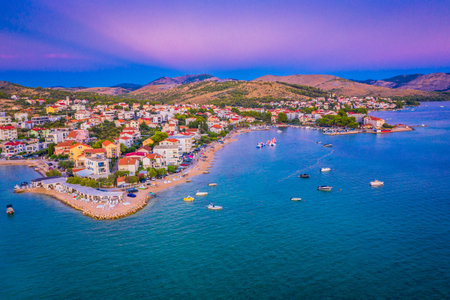 Drone photo of Zaboric at dusk showing glowing village lights, calm Adriatic shoreline, houses by the sea and a peaceful Mediterranean atmosphere under the fading evening skyの写真素材