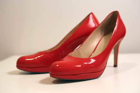 A pair of sexy and beautiful bright red leather high heels on top of a white surfaceの写真素材