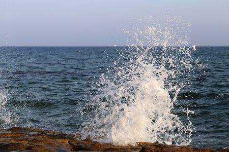 Waves hitting the rocky cliffs in a beach located in Cyprus, Europe, August 2019. This weather might be dangerous for water sports but simultaneously the waves and their splashes are pretty and wild.の写真素材