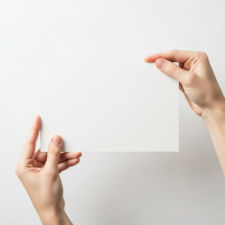 Hands holding paper square isolated on white backgroundの素材