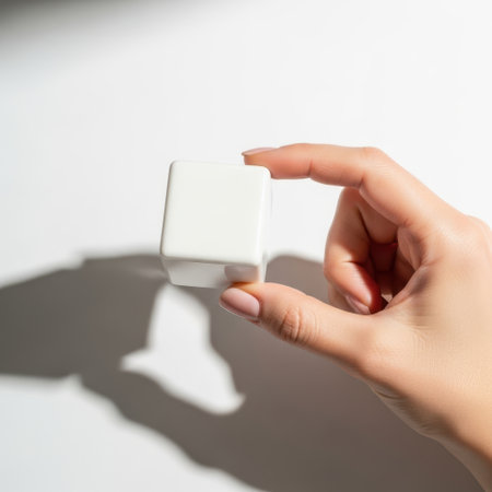 Hand holding white cube isolated on white backgroundの素材