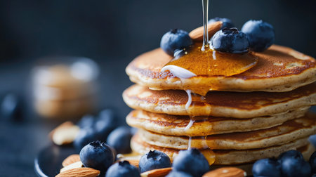 Indulge in this mouthwatering creation of fluffy pancakes, topped with ripe blueberries and drizzled with golden syrup, perfect for any breakfast or brunch occasion.の素材