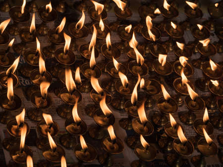 Large group of burning candles against dark backgroundの写真素材