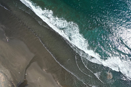 Aerial view of the ocean waves crashing on the sandy beach.の写真素材