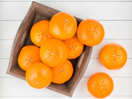 Fresh mandarins in a wooden basket on the tableの写真素材
