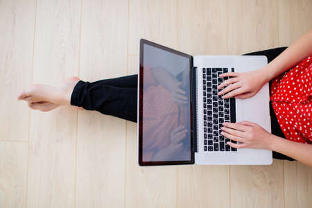 Top view of a young woman working place. Female hands tapping on the laptop keyboard.