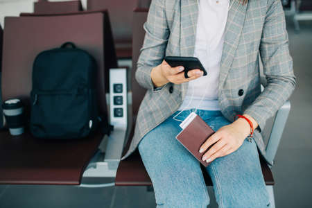 Young girl at the airport waiting for departure. Holding smartphone, passport and ticket.の写真素材