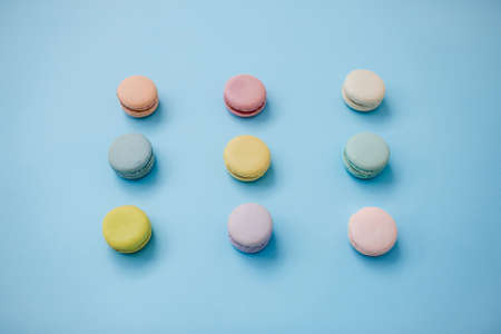 Top view of sweet French macaroon biscuits lying in three lines on pastel blue background.の写真素材