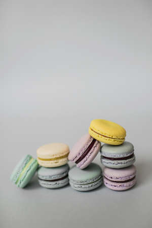Sweet colorful pile of French macaroon biscuits lying on pastel grey background.