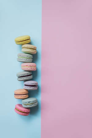 Macaron or macaroon biscuits on pastel blue and pink double background. Colorful almond cookies of pastel colors. Top view.の写真素材