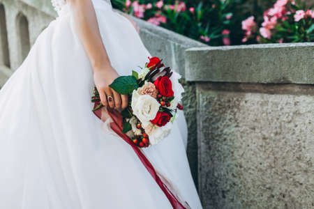 Wedding bouquet with bright flowers in brides hand. Close up, no face seen.の写真素材