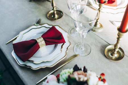 Beautifully served dinner table with golden forks and knifes, glasses for wine, candles standing around.の写真素材