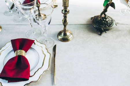 Overview of a beautifully served dinner table with golden knifes, wine glasses, candles.の写真素材