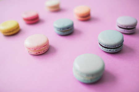 Multicolored macaron or macaroon biscuits on pastel pink background, lying in three raws. Almond cookies of pastel colors. Overview.の写真素材