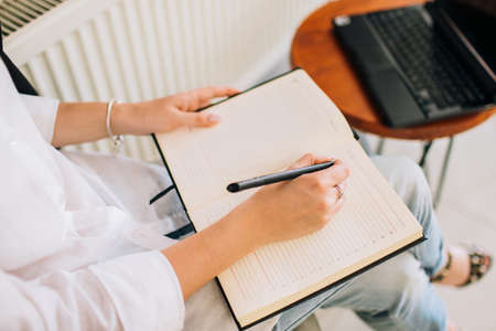 Female hands writing in a notepad, top view. Businesswoman working a cozy workspace.の写真素材