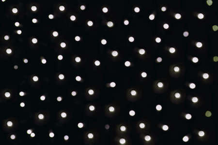 Silver lights with tint blurred bokeh, dark background with lots of flashing circles.の写真素材