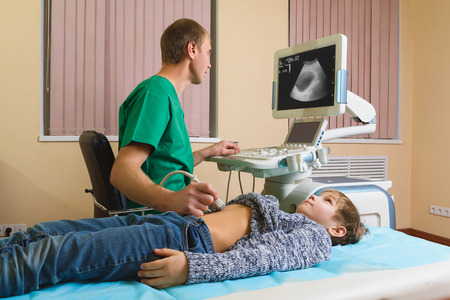 Doctor analyzing boy patient with abdomen ultrasound.