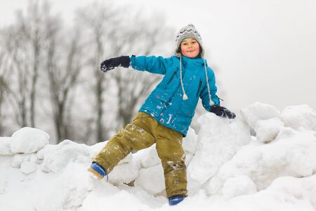 Happy baby boy playing snow in winter day.の写真素材