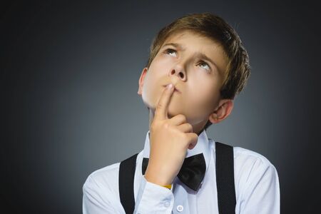 doubt, expression and people concept - boy thinking over gray background.の写真素材