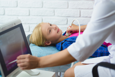 Female doctor examines girl patient with ultrasound in medical center.