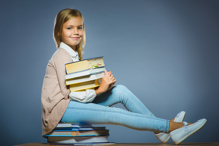 school concept. girl sitting on books and holding a book in hand.の写真素材