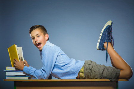 school concept. Boy lying on the desk and reading a book.の写真素材