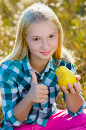 Cute little girl or teenager eaten healthy and juicy pear outdoor.の写真素材
