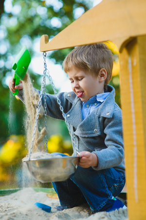 happy little boy playing in sandbox at playground.の写真素材