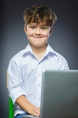 Cute little smiling boy using laptop isolated grey background.の写真素材
