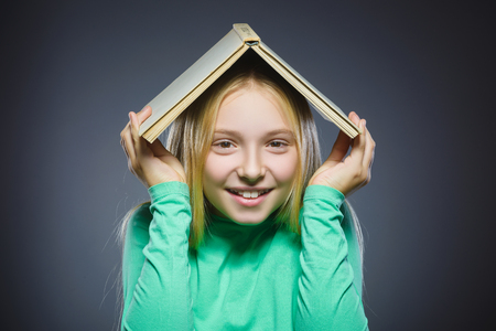 wondering girl with book over head. Closeup Portrait of handsome teen in casual shirt on grey background. studies concept.の写真素材
