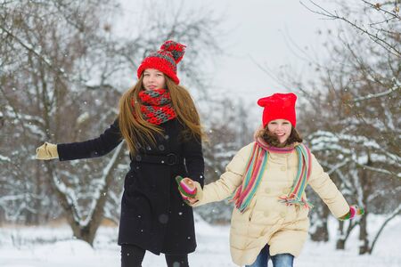 two happy girls playing on the snow in winter day outdoorの写真素材