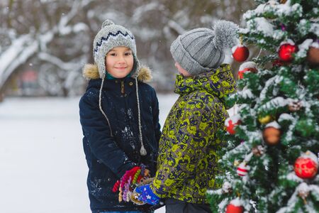 Two happy boys or a friends near Christmas tree outdoorの写真素材