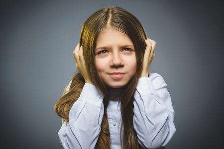 Little girl with astonished expression while standing against grey backgroundの写真素材