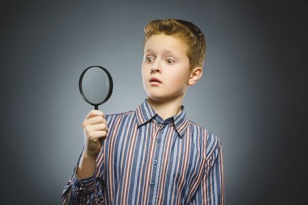 Boy See Through Magnifying Glass, Kid Eye Looking with Magnifier Lens over Grayの写真素材