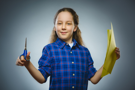 Cheerful or happy girl with scissors and colored paper isolated on grayの写真素材