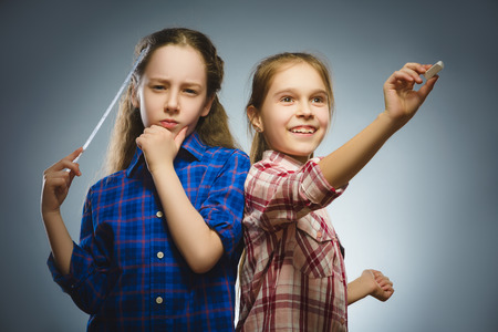 Closeup Thoughtful girl and happy girl with school suppliesat isolated on Grayの写真素材