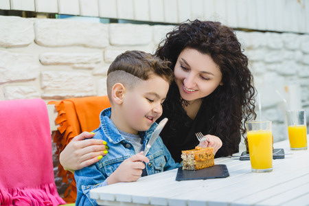 Boy and mother or happy family having healthy breakfast in resort cafe outdoorの写真素材