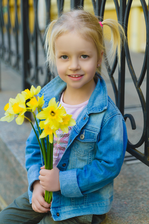 Beautiful little girl posing with a large bouquet of flowersの写真素材