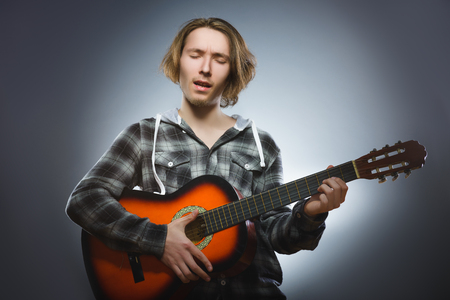 Caucasian boy playing on acoustic guitar. Teenager with classic wooden guitarの写真素材