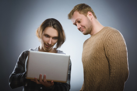 Surprised man and wondering teenager looking at laptopの写真素材