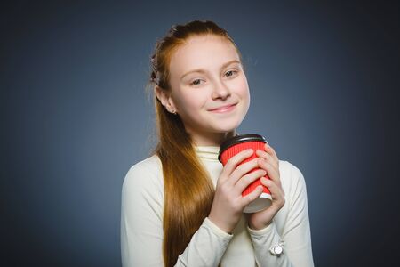 teenage girl drink red cup of coffee isolated on gray background