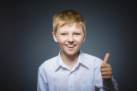 Closeup portrait successful happy boy show thumb up isolated grey background.の写真素材