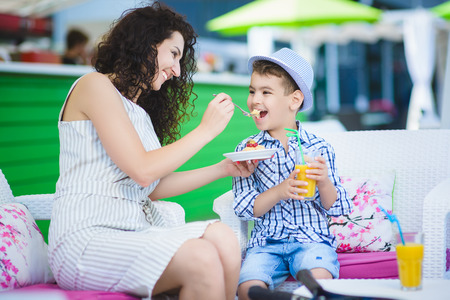 Boy and mother or happy family having healthy breakfast in resort cafe outdoorの写真素材