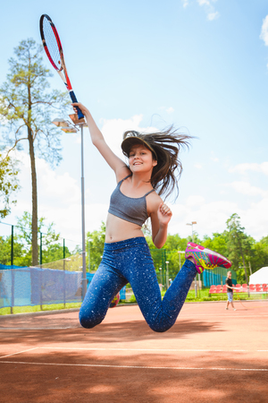 Cute girl playing tennis and posing in court outdoor