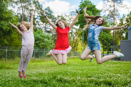 Children jumping on grass in parkの写真素材