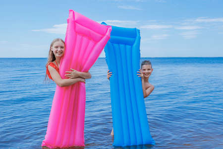 children bathe in inflatable mattresses in summer at sea