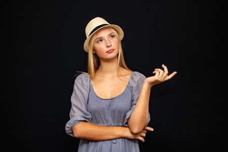 Beautiful girl in a hat, expresses emotions, surprise, close-up on a dark background.の写真素材