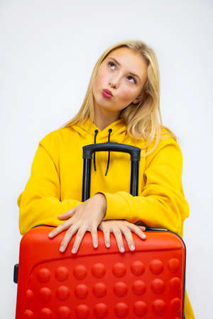 Traveling with a suitcase, happy, cheerful, beautiful blonde under an umbrella, white background, close-up.の写真素材